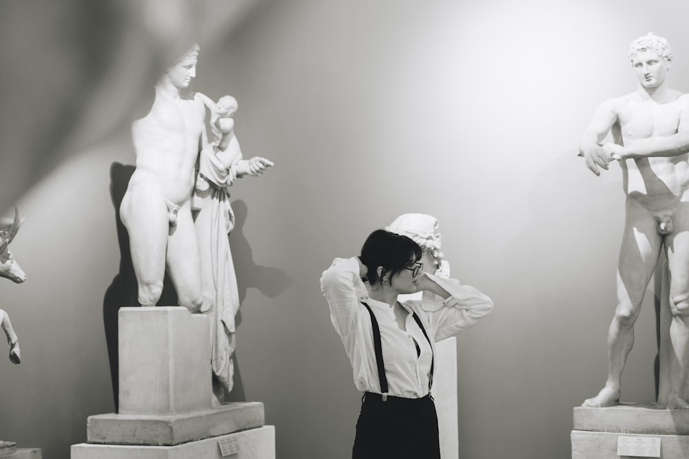 woman in white coat standing beside white statue