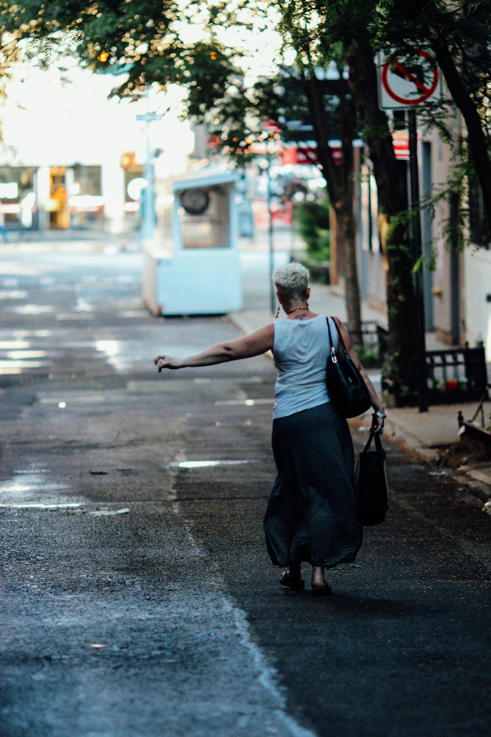 Mujer en vestido negro caminando en la acera durante el día