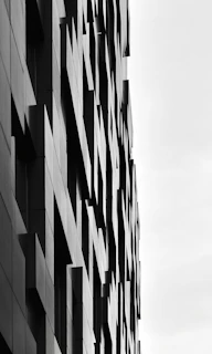 A striking modern architectural facade with sharp angles and deep shadows against a crisp white sky.