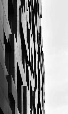 A striking modern architectural facade with sharp angles and deep shadows against a crisp white sky.