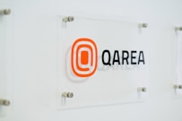 a glass sign with a qarea logo on it