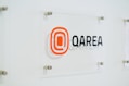 a glass sign with a qarea logo on it
