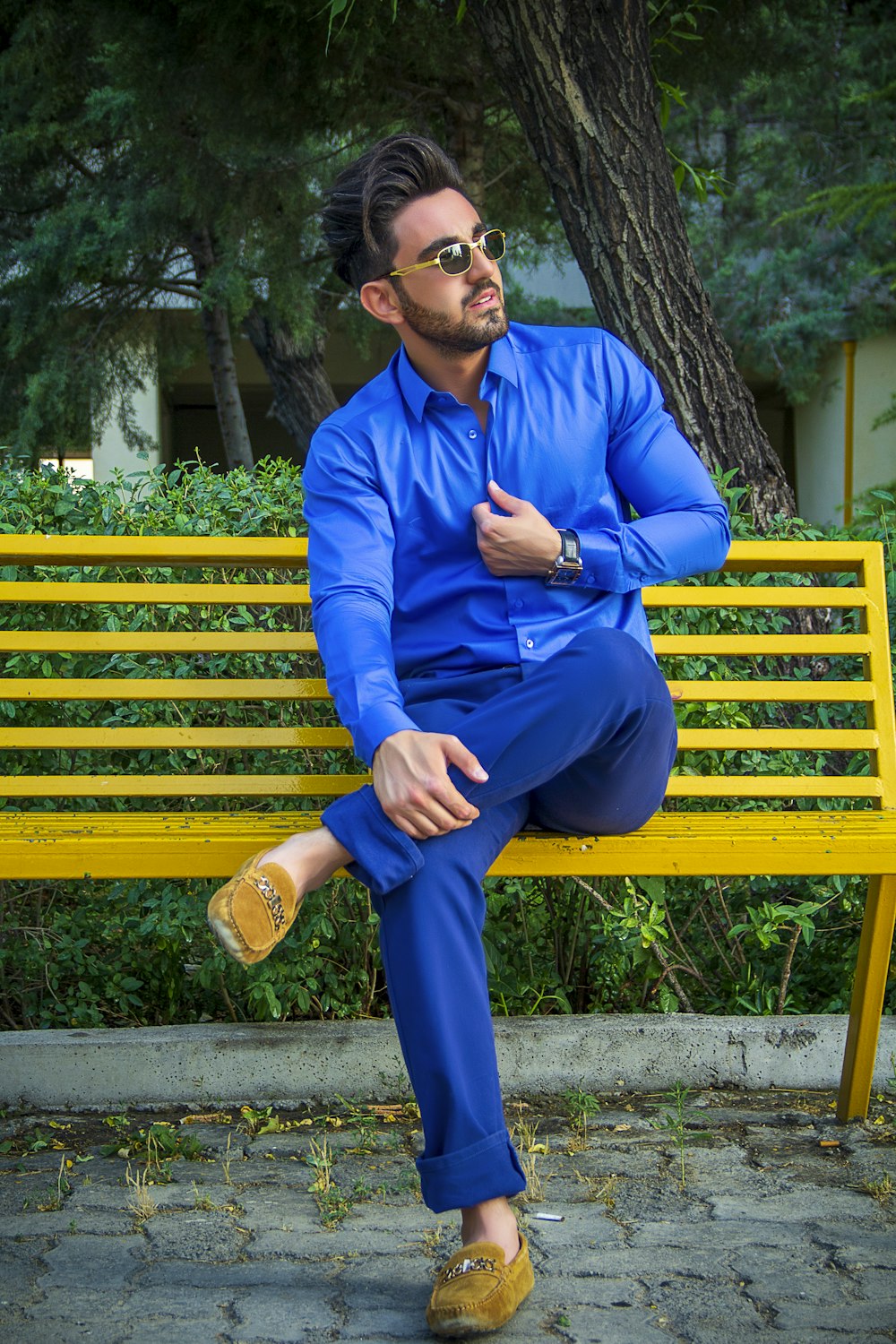 man in blue dress shirt and blue pants sitting on yellow wooden bench