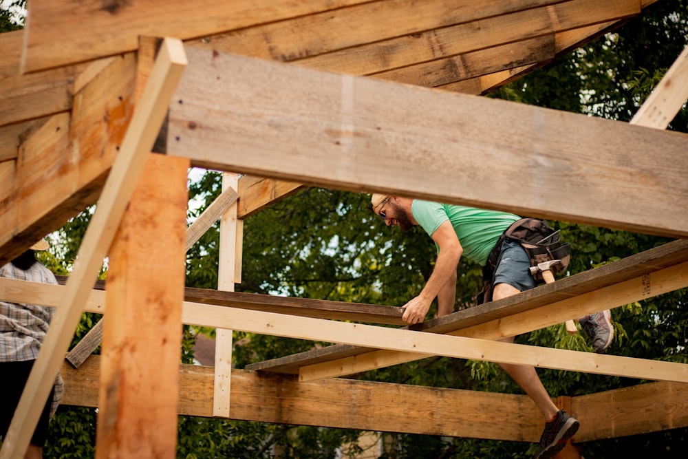 Homme en T-shirt bleu et short noir grimpant sur un pont en bois marron