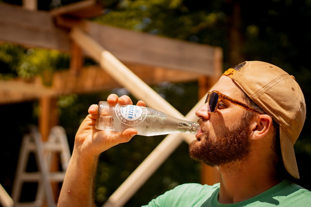 man in green crew neck shirt holding clear plastic bottle