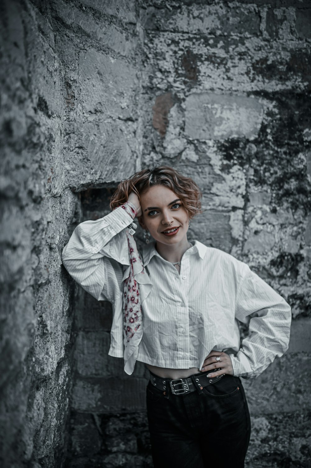 woman in white dress shirt leaning on grey concrete wall