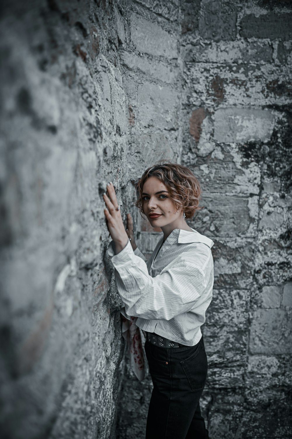 woman in white dress shirt leaning on wall