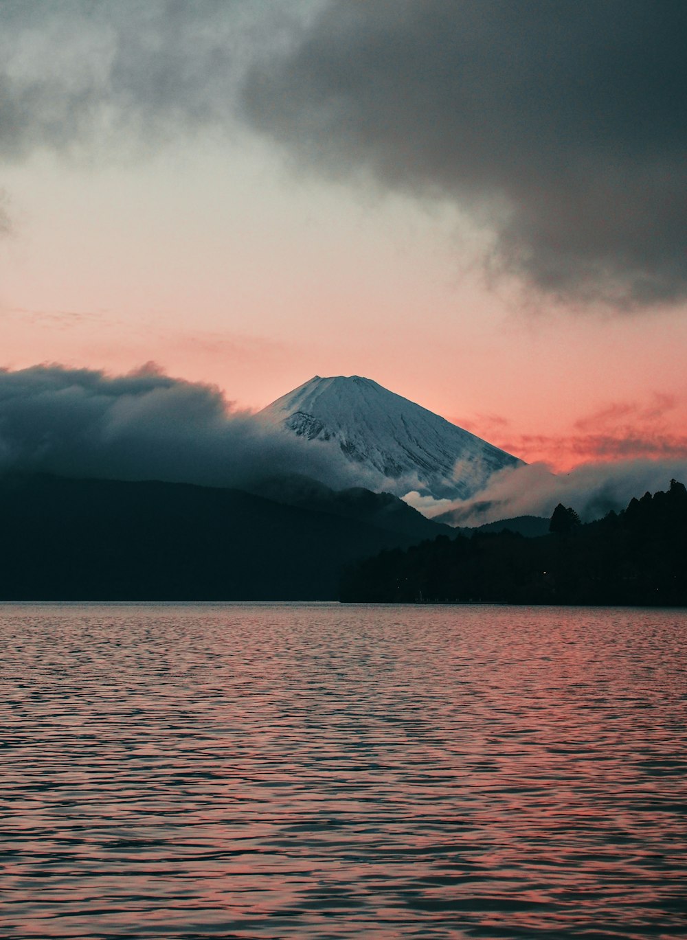 body of water near mountain under cloudy sky during daytime