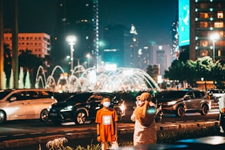 man and woman standing on road during night time