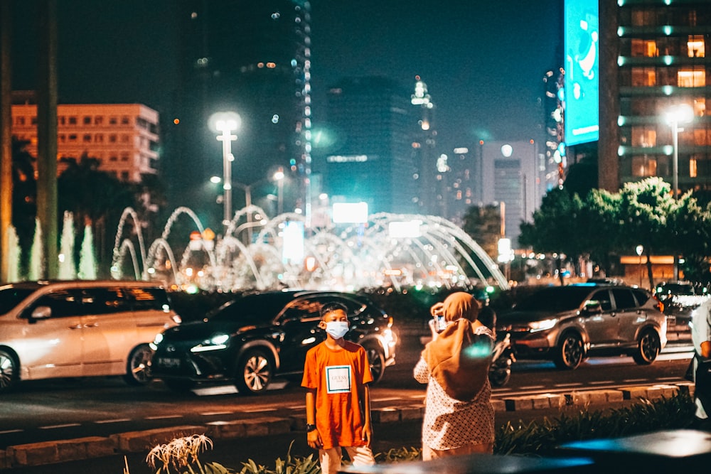 man and woman standing on road during night time