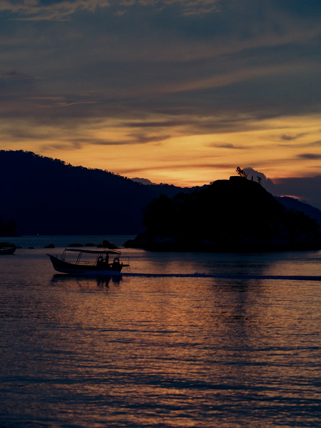 silhouette of boat on body of water during sunset
