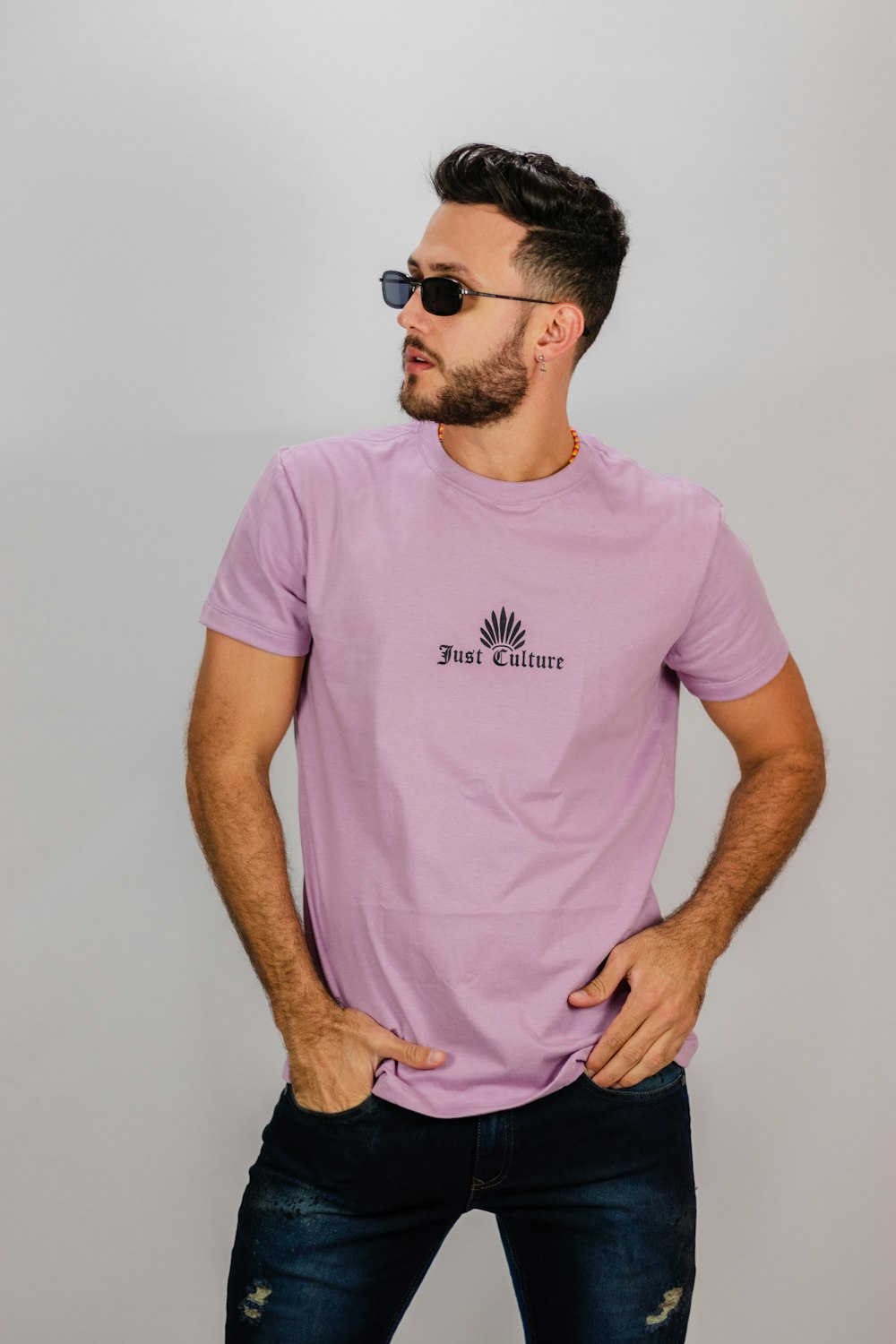 Homme en T-shirt rose à col rond portant des lunettes de soleil noires