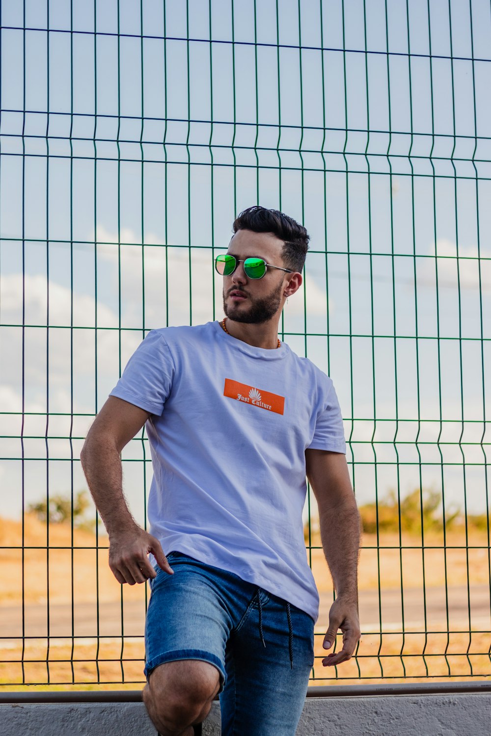 man in white crew neck t-shirt and blue denim jeans wearing green sunglasses