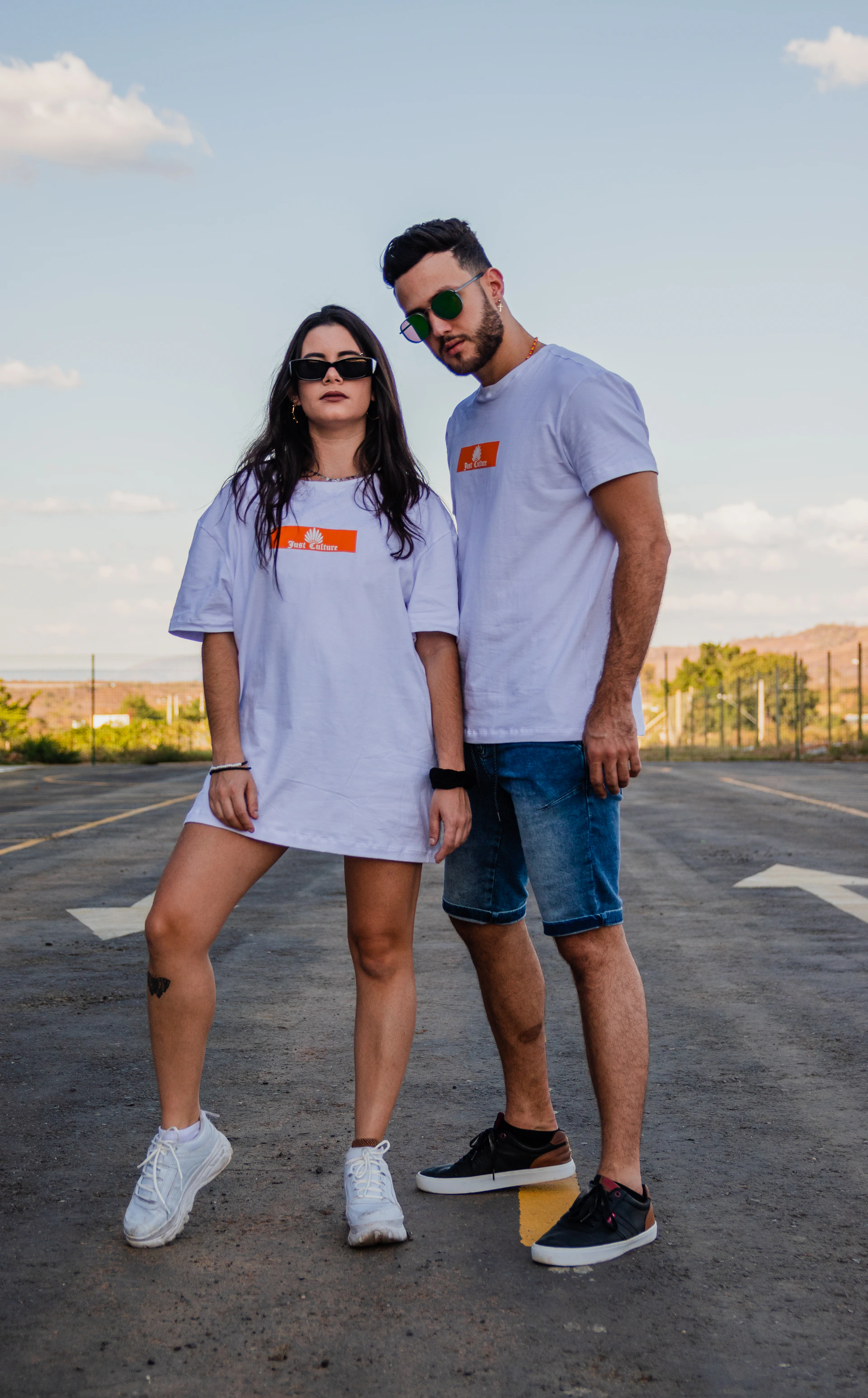 woman in white crew neck t-shirt and blue denim shorts standing on gray asphalt road