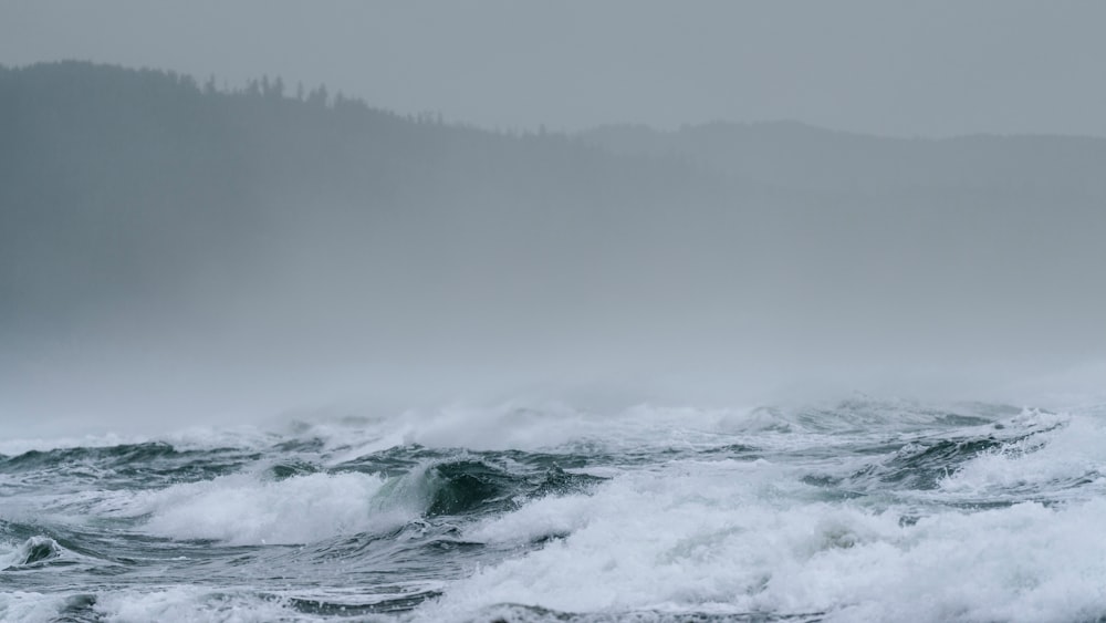 ocean waves crashing on shore during foggy weather