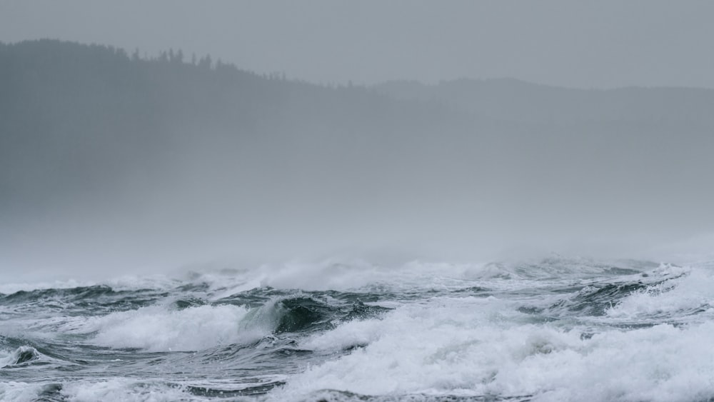 ocean waves crashing on shore during foggy weather