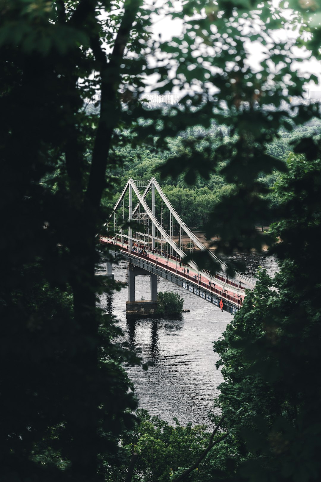 brown wooden bridge over river surrounded by green trees during daytime