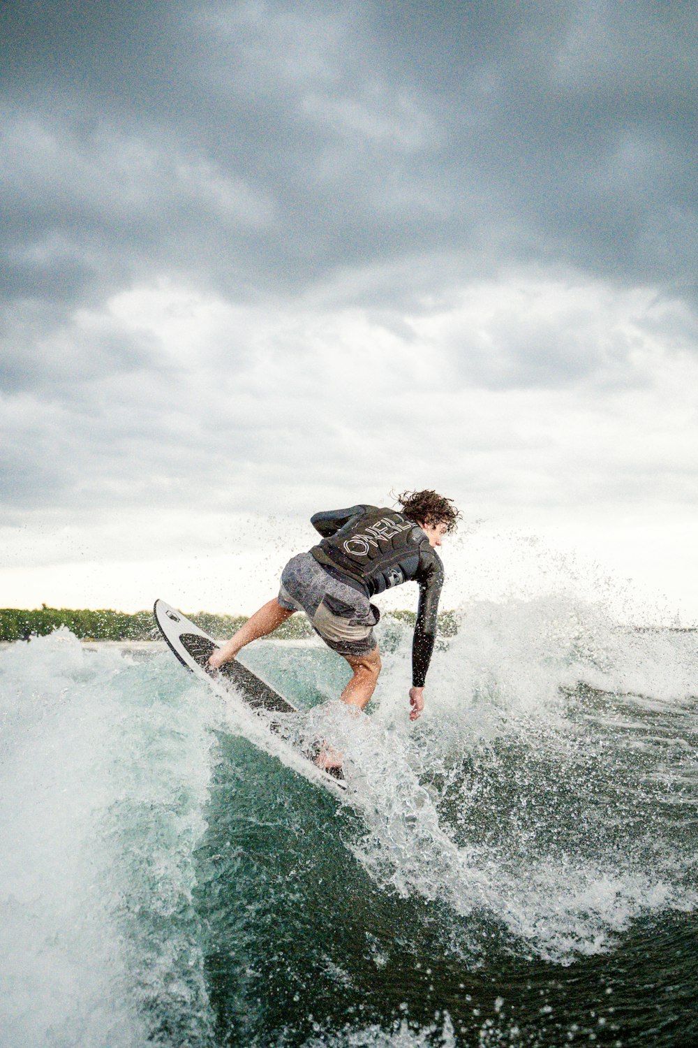 man in black and white wet suit riding white surfboard on sea waves during daytime