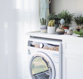 white front load washing machine beside white wooden cabinet