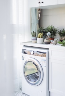 white front load washing machine beside white wooden cabinet