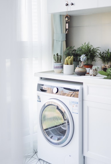 white front load washing machine beside white wooden cabinet