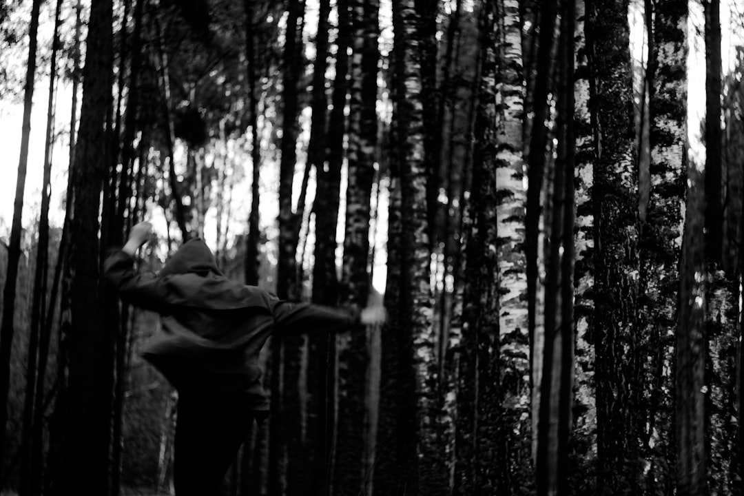 grayscale photo of man in jacket and pants in forest