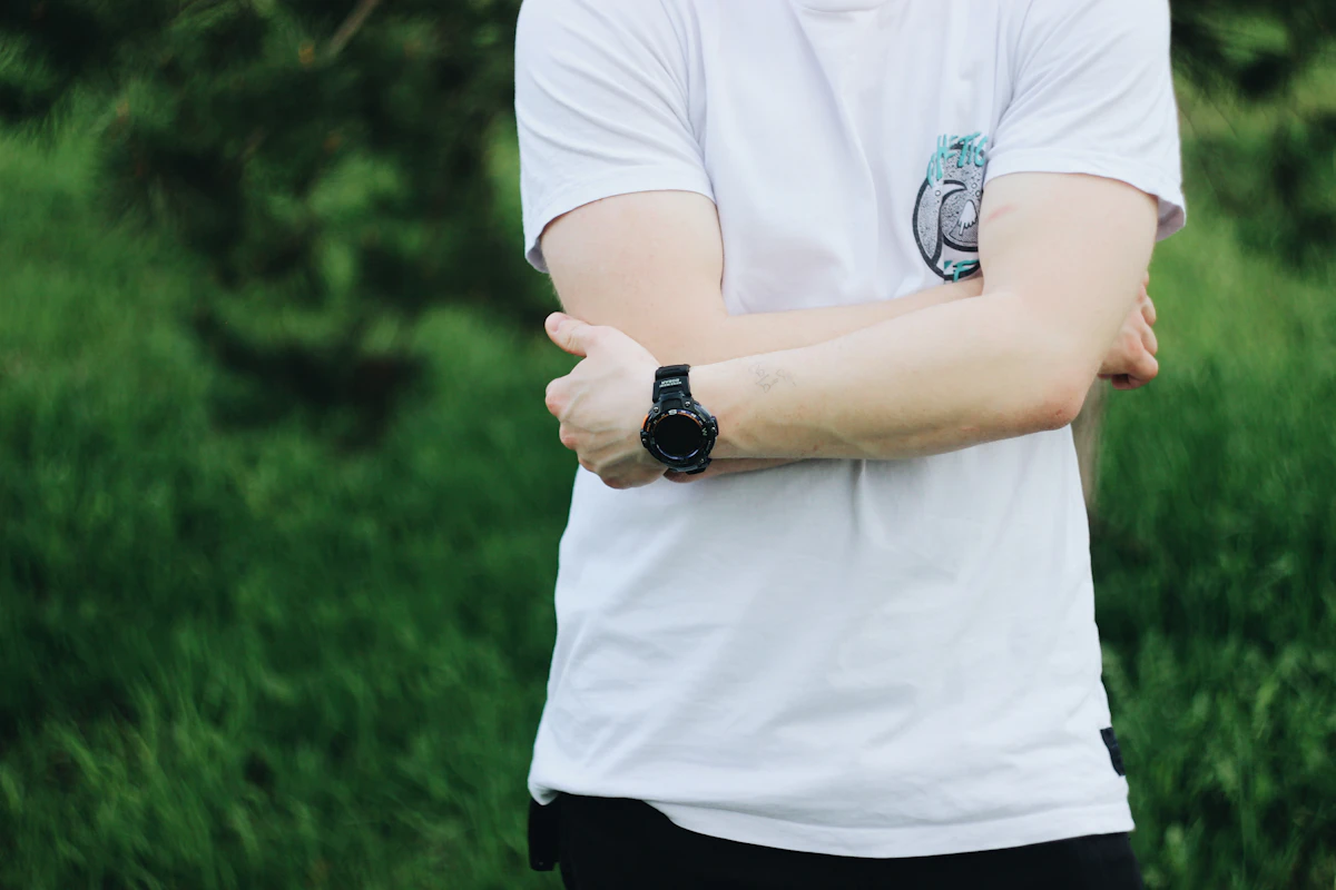person in white polo shirt and black pants wearing black round analog watch