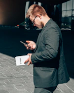 man in black suit jacket holding black smartphone