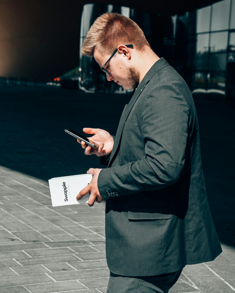 man in black suit jacket holding black smartphone