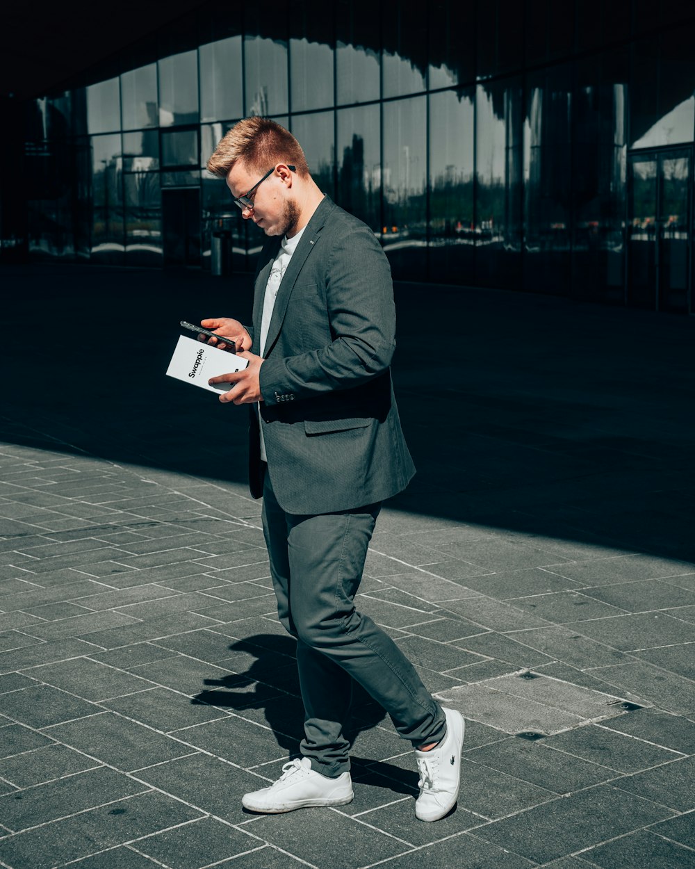 man in black suit jacket and gray pants holding book
