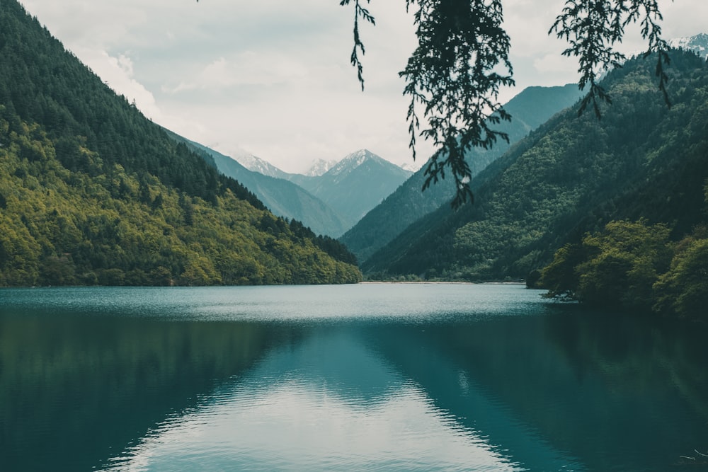 green lake surrounded by green mountains during daytime