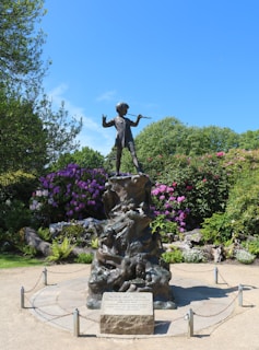 brown statue of man near green trees during daytime