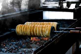 Close-up of sizzling pide dough topped with fresh ingredients over glowing mangal coals.