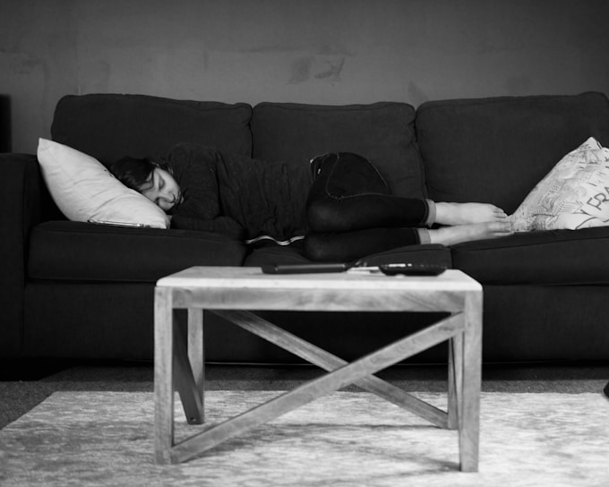 grayscale photo of woman lying on couch