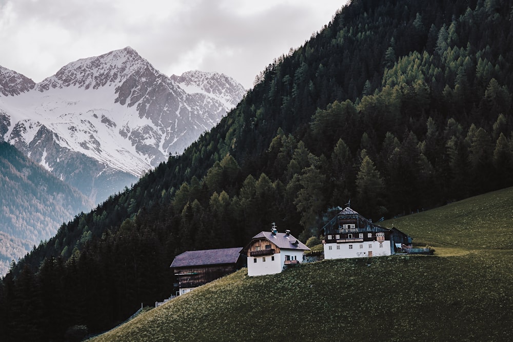 white and brown house near green trees and mountain under white clouds during daytime