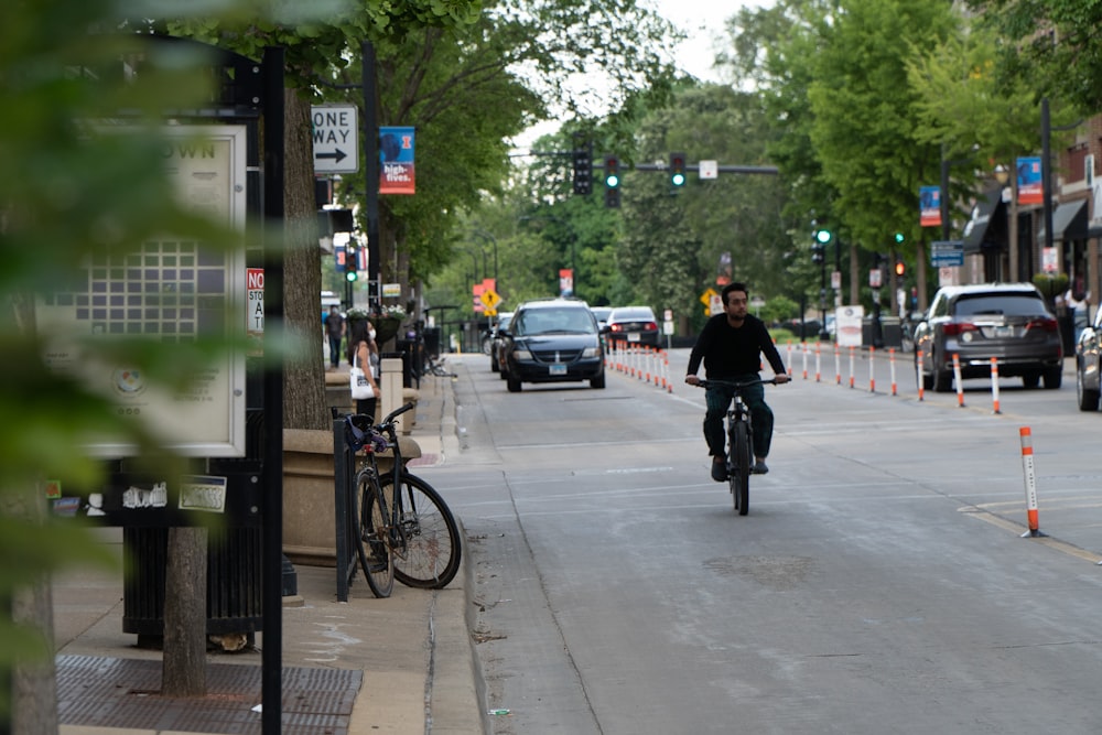 man in black jacket riding bicycle on road during daytime