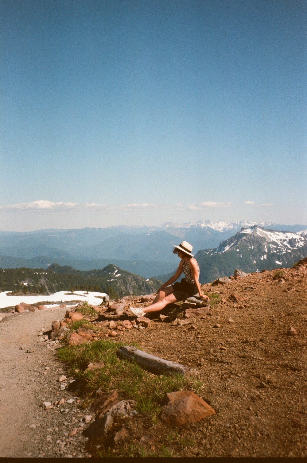 man in black t-shirt sitting on brown rock near lake during daytime