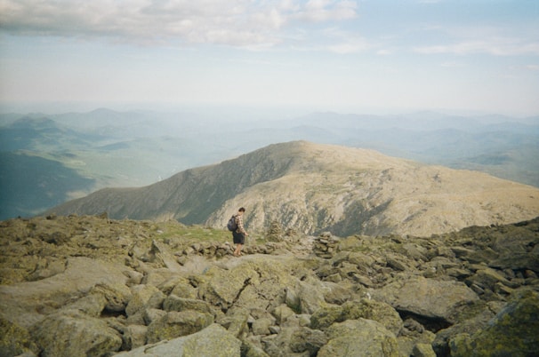A scenic mountain trail with a solo female hiker pausing to take in the view.