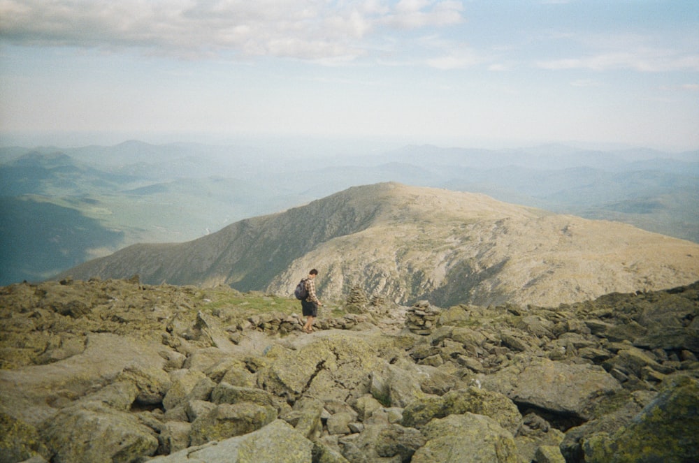 person standing on rocky mountain during daytime