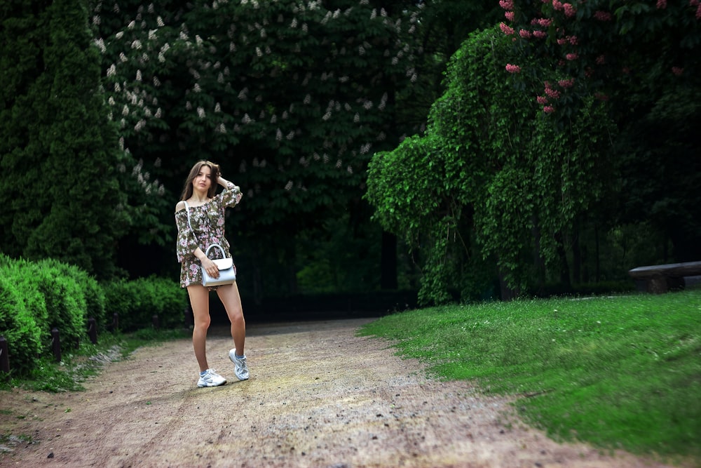 woman in black and white floral dress standing on brown dirt road during daytime