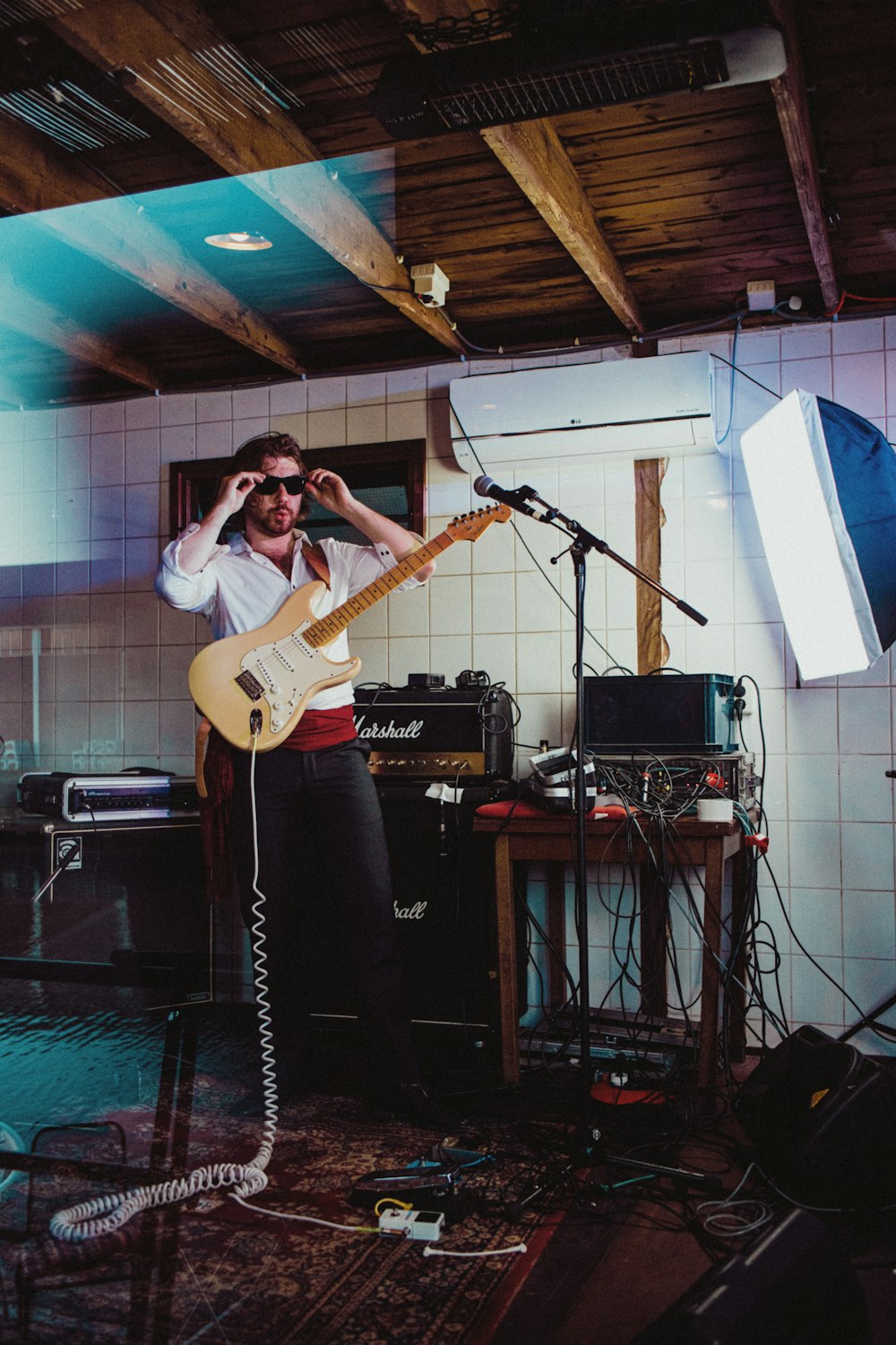 man in white shirt playing guitar on stage