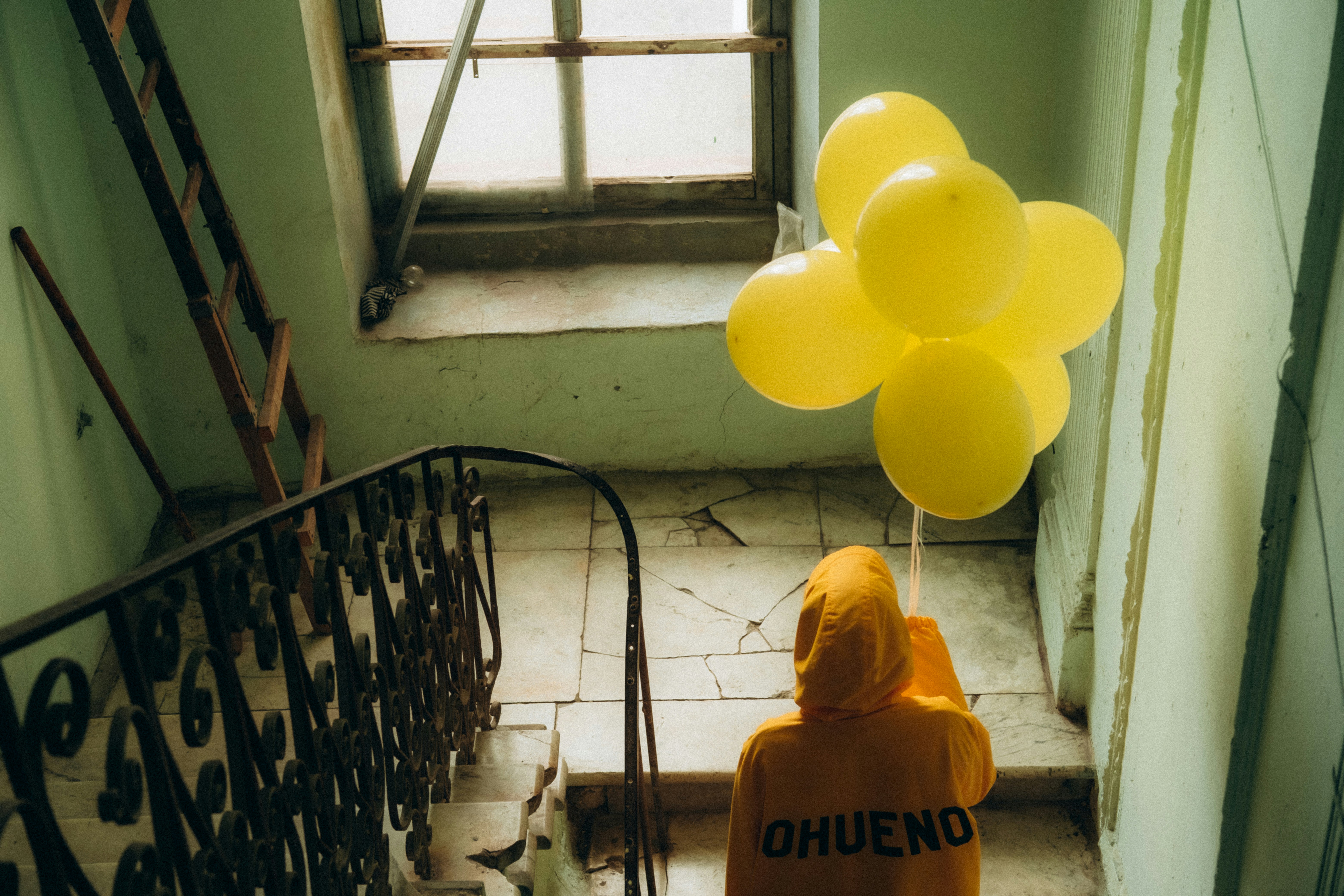homem em capuz amarelo sentado nas escadas
