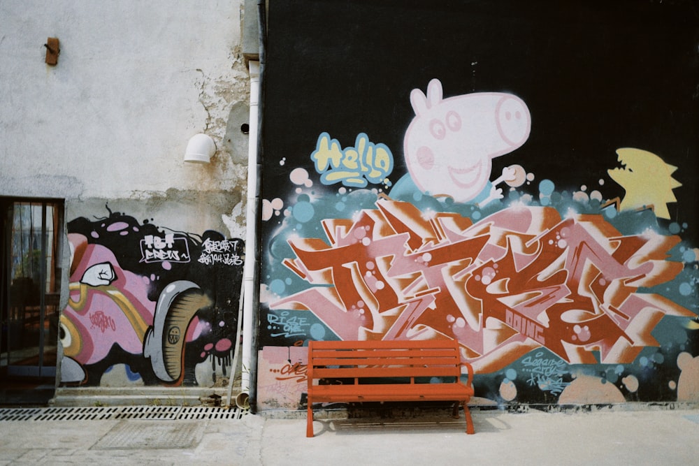 blue wooden bench beside wall with graffiti