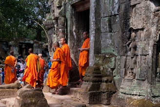 group of people in orange robe walking on gray concrete stairs during daytime