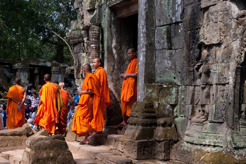 group of people in orange robe walking on gray concrete stairs during daytime