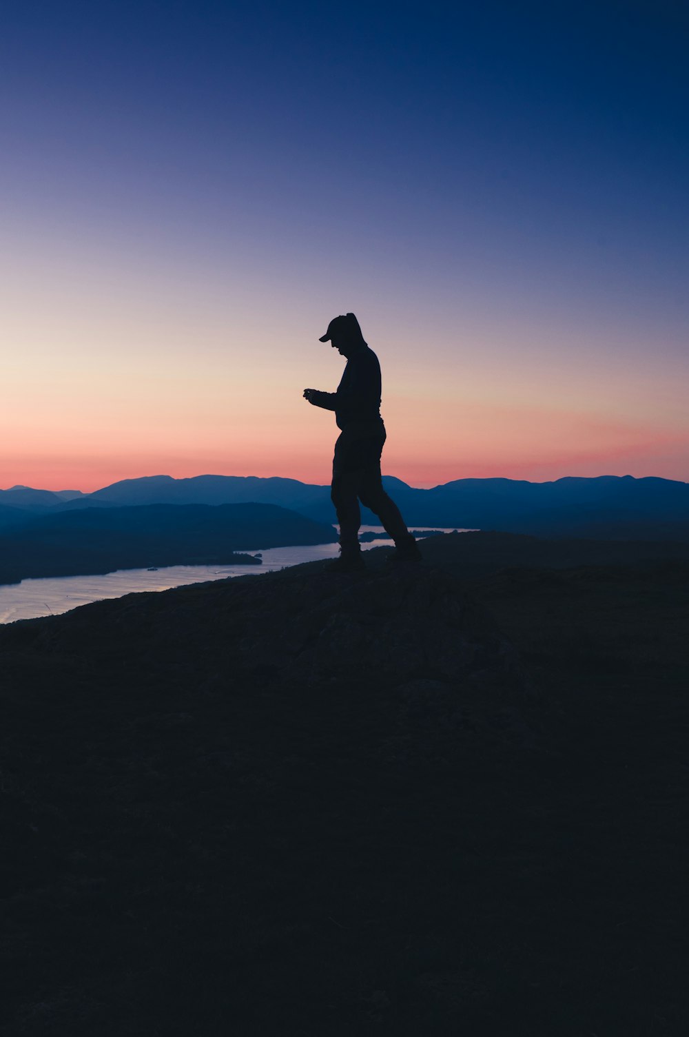 a man standing on top of a hill next to a body of water