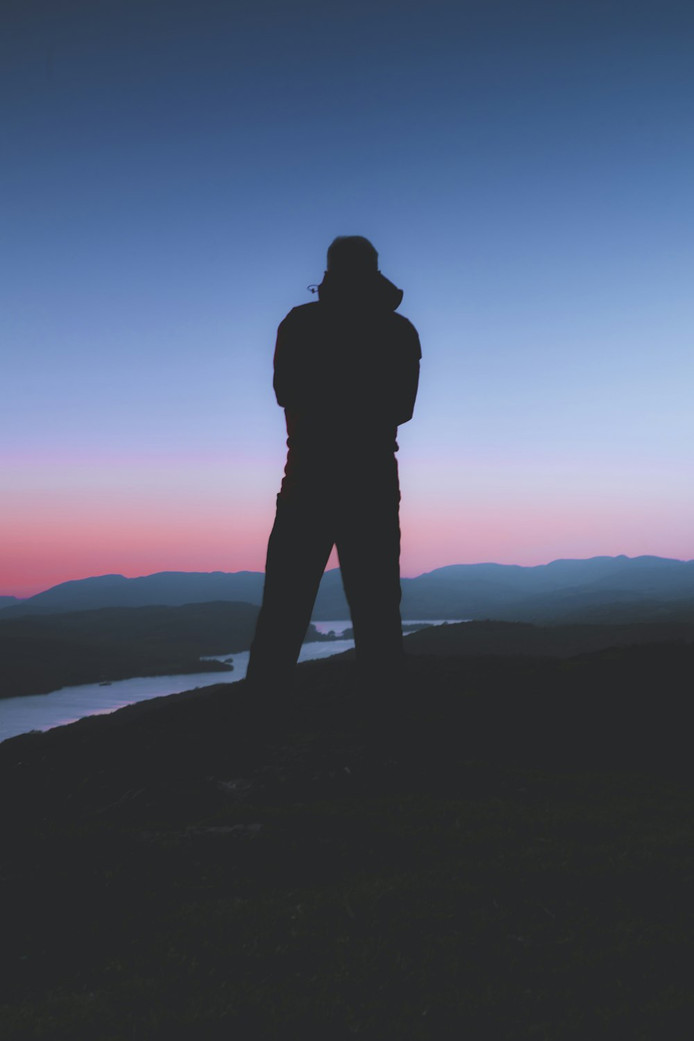 a person standing on top of a hill next to a body of water