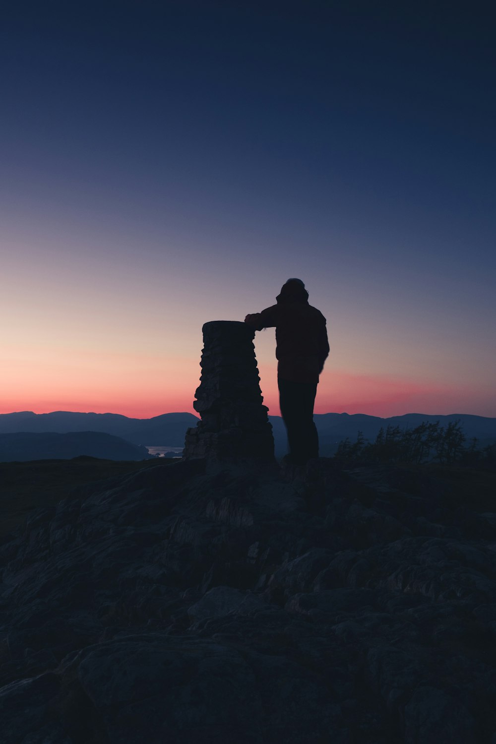 una persona in piedi sulla cima di una montagna al tramonto