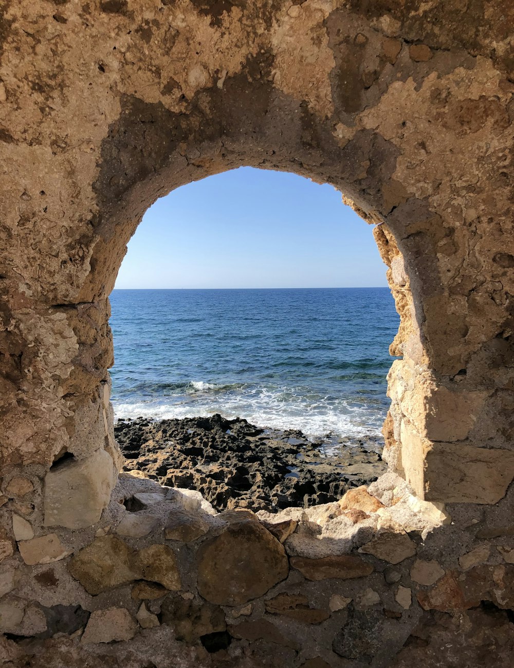 brown concrete arch near sea during daytime