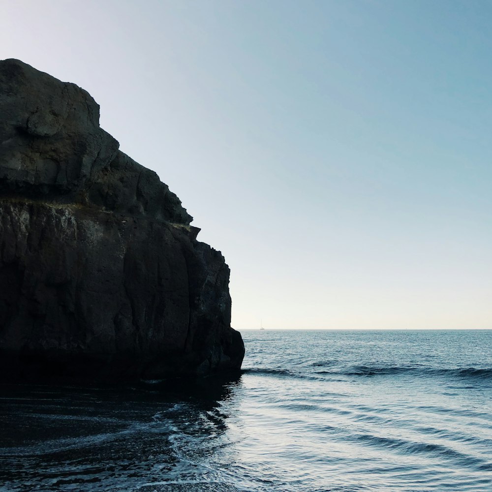 black rock formation on sea during daytime